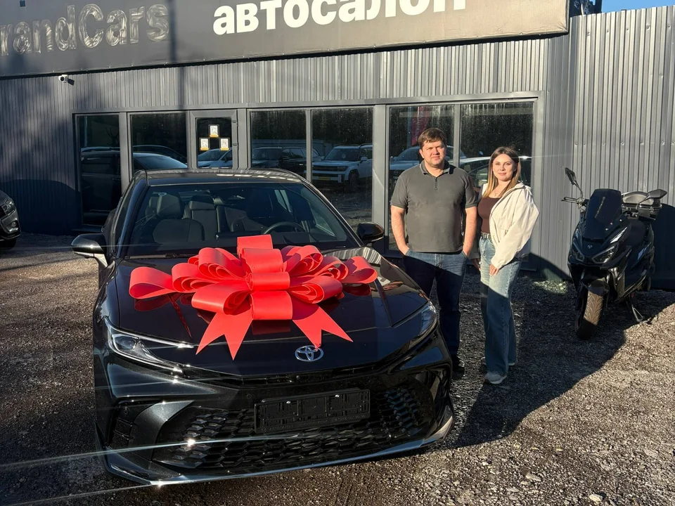 Клиенты автосалона рядом с приобретённым автомобилем Toyota