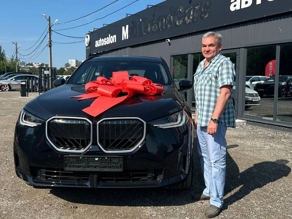 Клиент автосалона рядом с приобретённым автомобилем BMW
