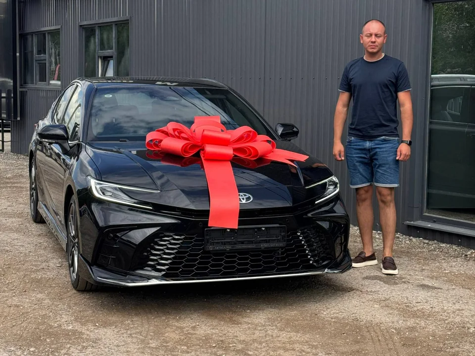 Клиент автосалона рядом с приобретённым автомобилем Toyota