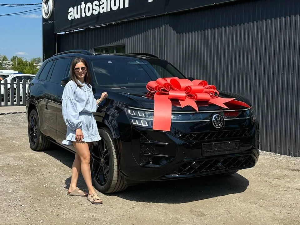 Клиент автосалона рядом с приобретённым автомобилем Volkswagen